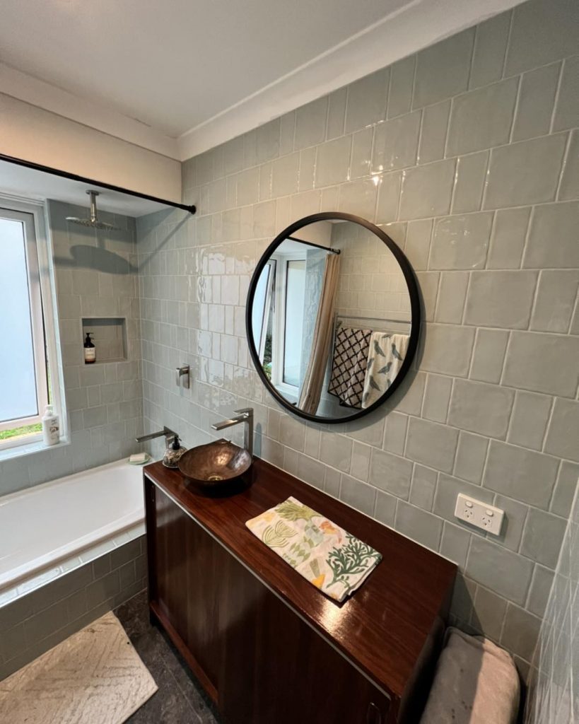 Contemporary bathroom with circular mirror and dark wooden vanity.